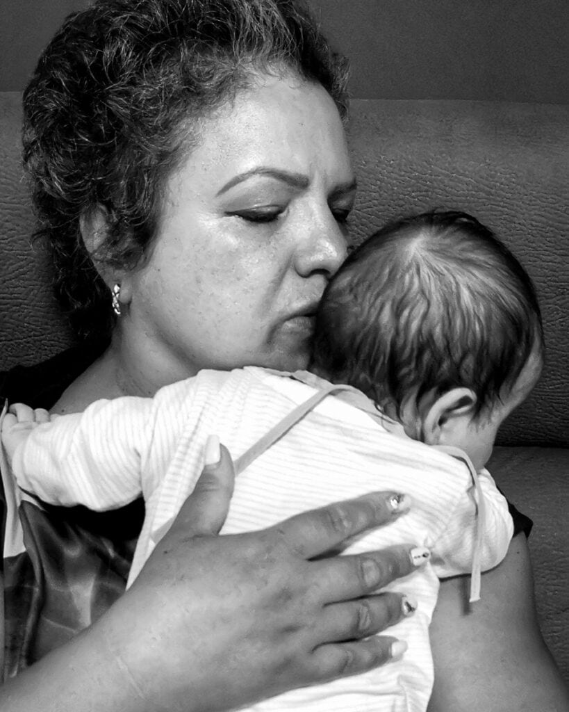 Fotografie Botez Oradea – Emoția Mamei și Copilului - FotoMistic Mamă ținându-și bebelușul în brațe la botez – fotografie emoționantă realizată în Oradea